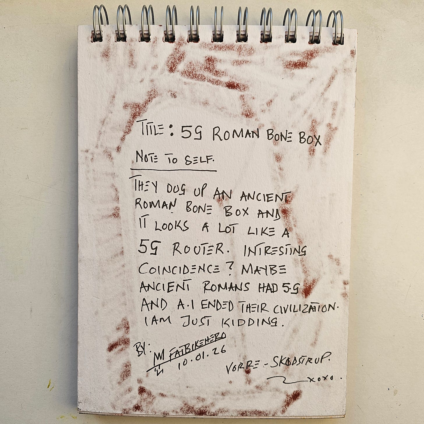 Alt Text: A handwritten sketchbook page by artist FatbikeHero, dated 10.01.26. The text reads "Title: 5G Roman Bone Box" and jokingly compares an ancient Roman bone box to a 5G router, suggesting AI ended Roman civilization. The paper has textured brown ink smudges around the edges.