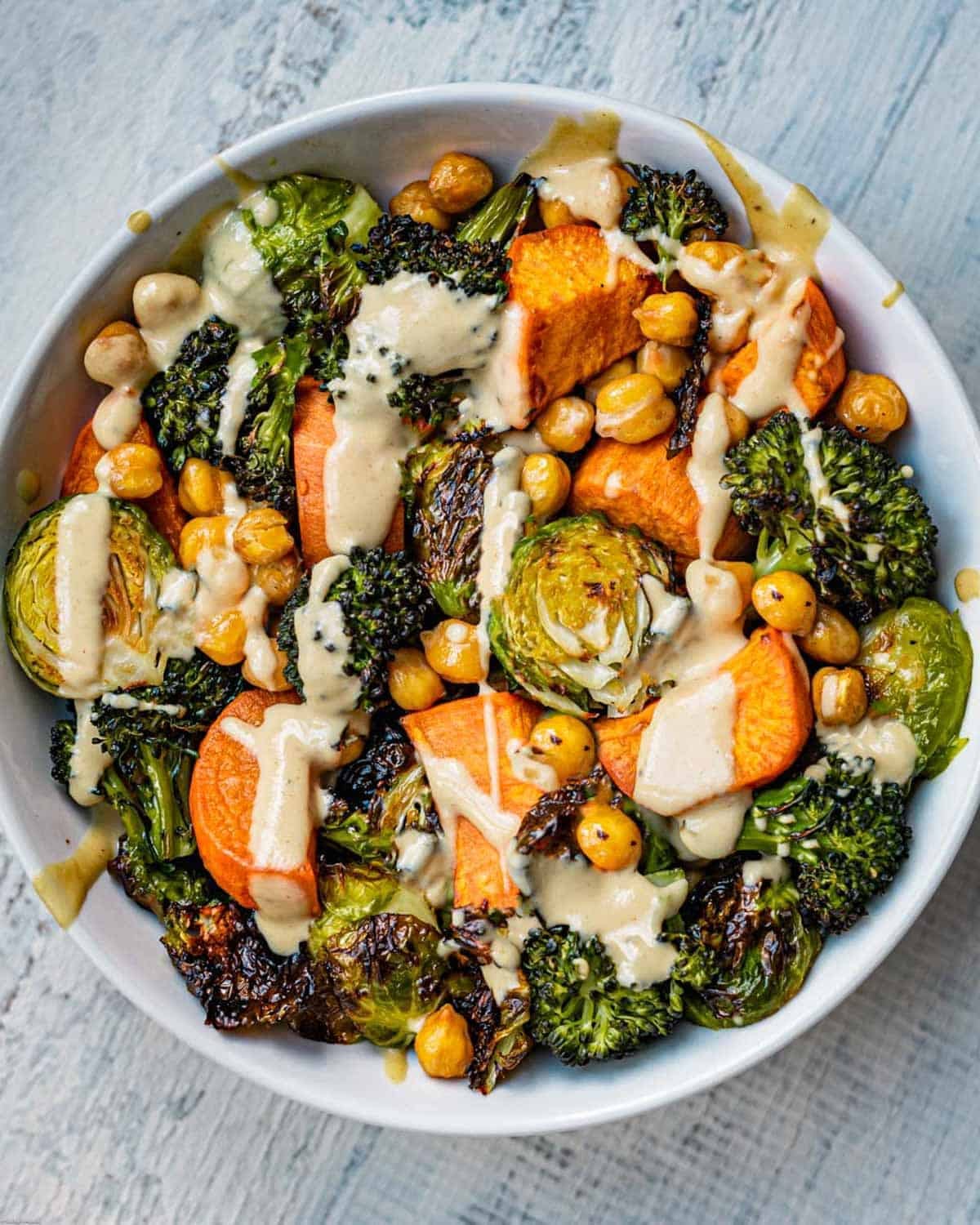 Bowl of roasted sweet potato, crispy chickpeas, charred broccoli, and roasted Brussels Sprouts.