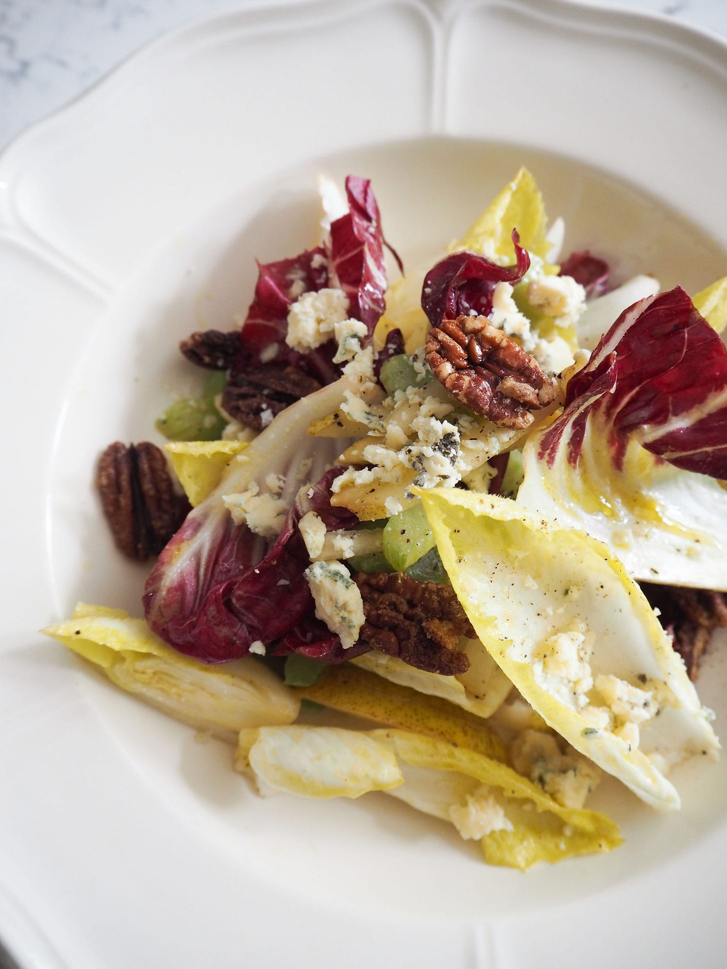 A bowl of salad leaves with cheese and pecan nuts