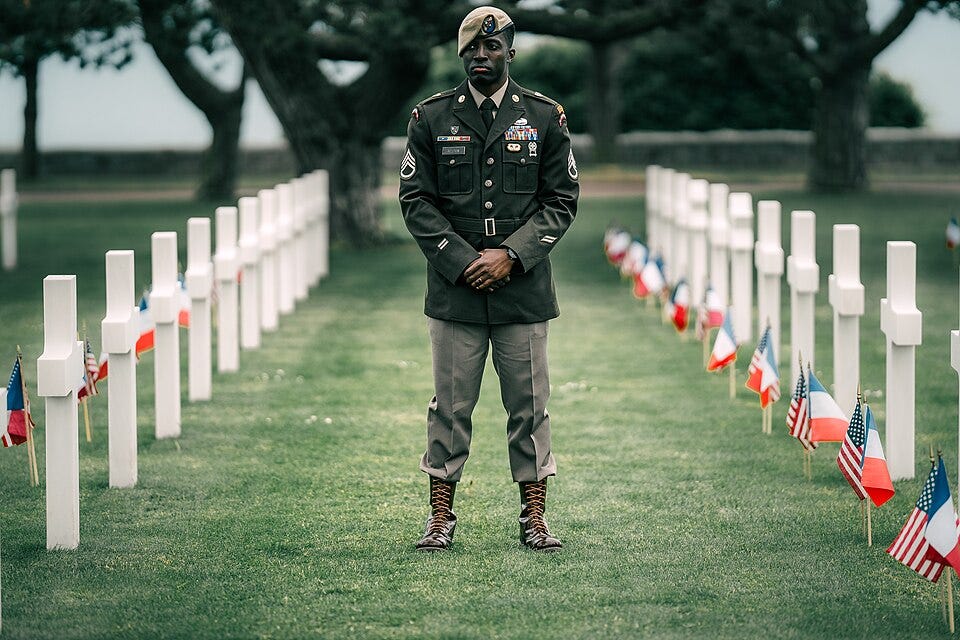 A person in military uniform standing in a field of white crosses

AI-generated content may be incorrect.
