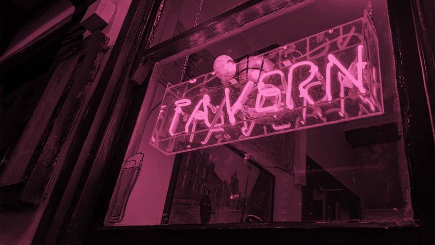 An illuminated sign in a pub window that reads "Tavern".