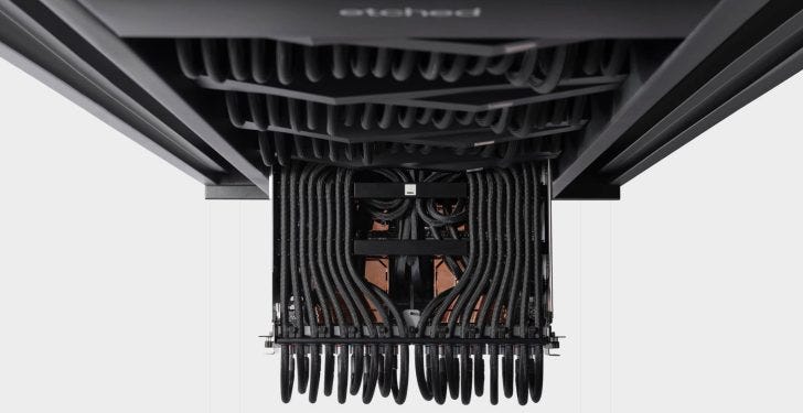 A detailed underside view of a data center rack with dense black cabling, featuring an 'etched' logo on the metal surface. A detailed underside view of a data center rack with dense black cabling, featuring an 'etched' logo on the metal surface.