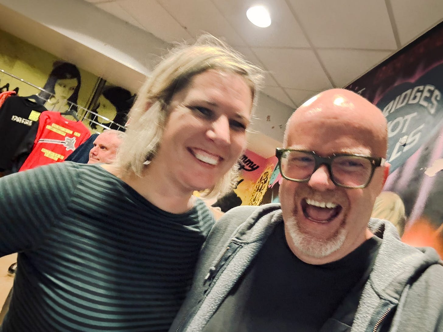 Scott Hamilton and Rachael Wood smiling at the merch table after the gig