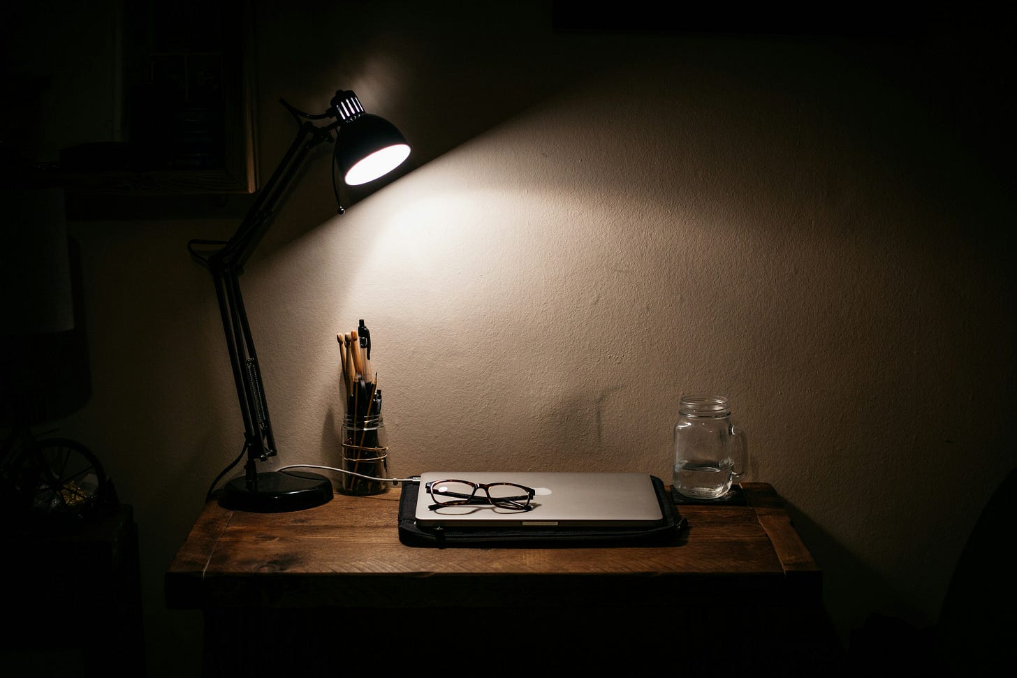 A writing desk with laptop and stationery, gently lit by a lamp in the evening