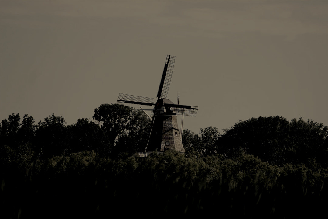 a windmill in a field with trees in the background a windmill in a field with trees in the background