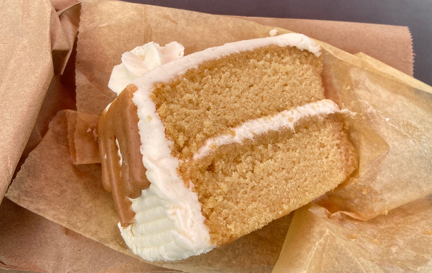 A piece of maple spice cake sits atop a sheet of brown wax paper.
