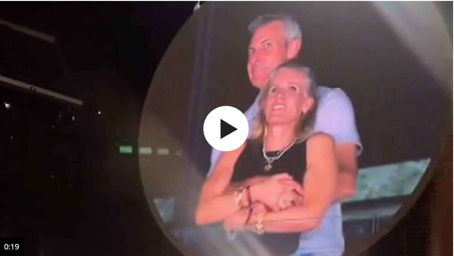 Image of video clip of embracing couple, Andy Byron Kristin Cabot, on the jumbotron at a Coldplay concert.