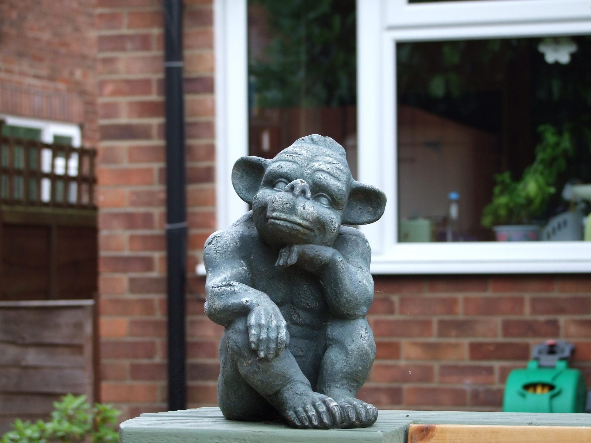 The photo of a home garden with a grey statue of a goblin The photo of a home garden with a grey statue of a goblin