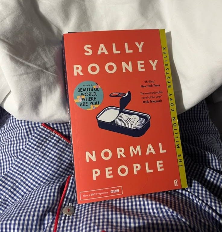 This may contain: a book sitting on top of a bed next to a white pillow and blue checkered bedspread