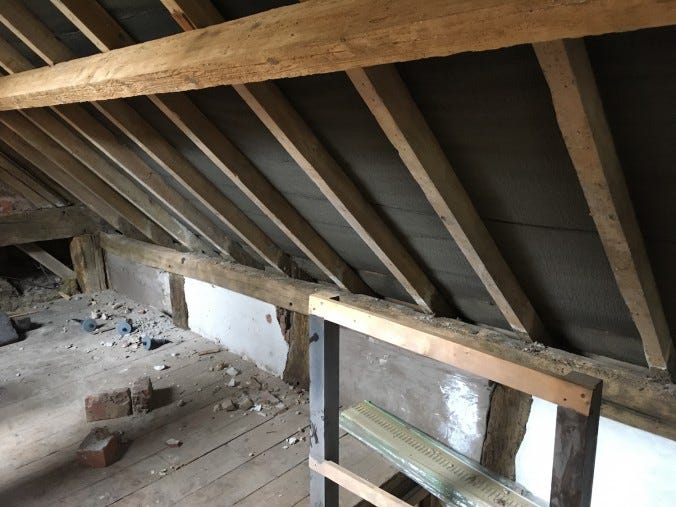 Messy attic with sloping roof and no bricks or soffit.