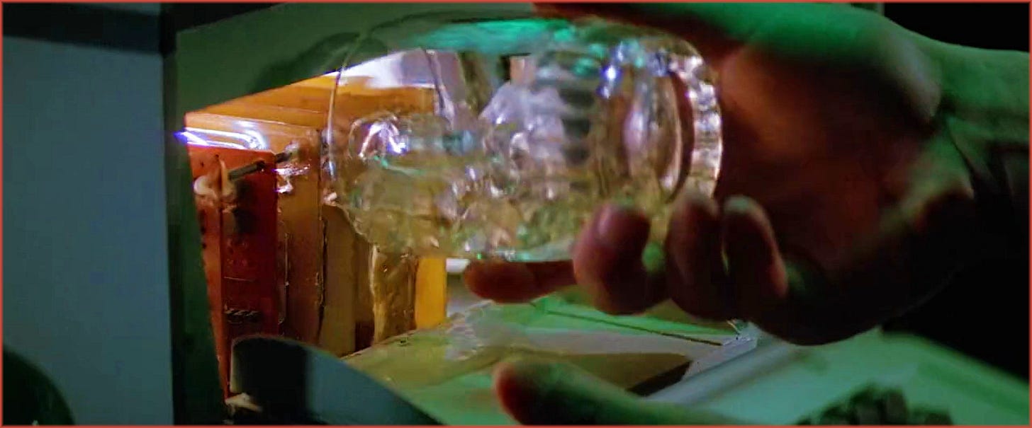Close-up from The Thing (1982): MacReady's hand pouring whiskey into the circuitry of an electronic chess computer, lit in blue and green. The act of sabotage that foreshadows the film's ending.