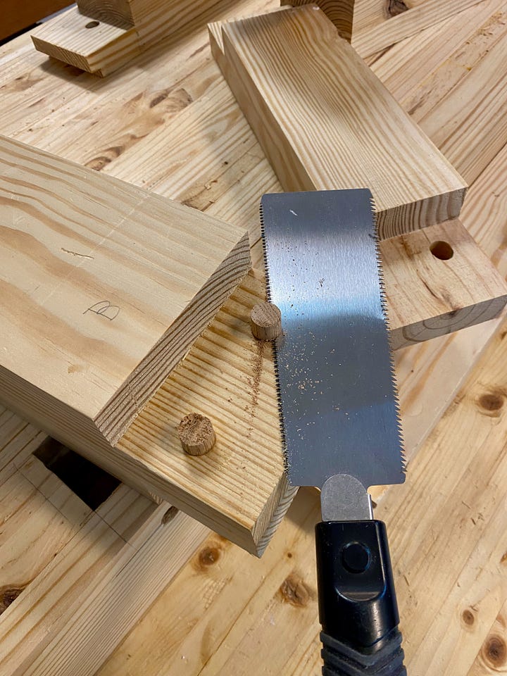 Drilling holes in the side of a workbench top, then filling holes with dowels and making new holes.