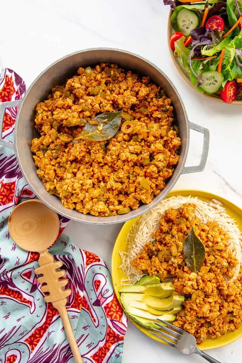 Picadillo de Pavo in a caldero next to a bowl of salad and a serving of turkey picadillo. Picadillo de Pavo in a caldero next to a bowl of salad and a serving of turkey picadillo.