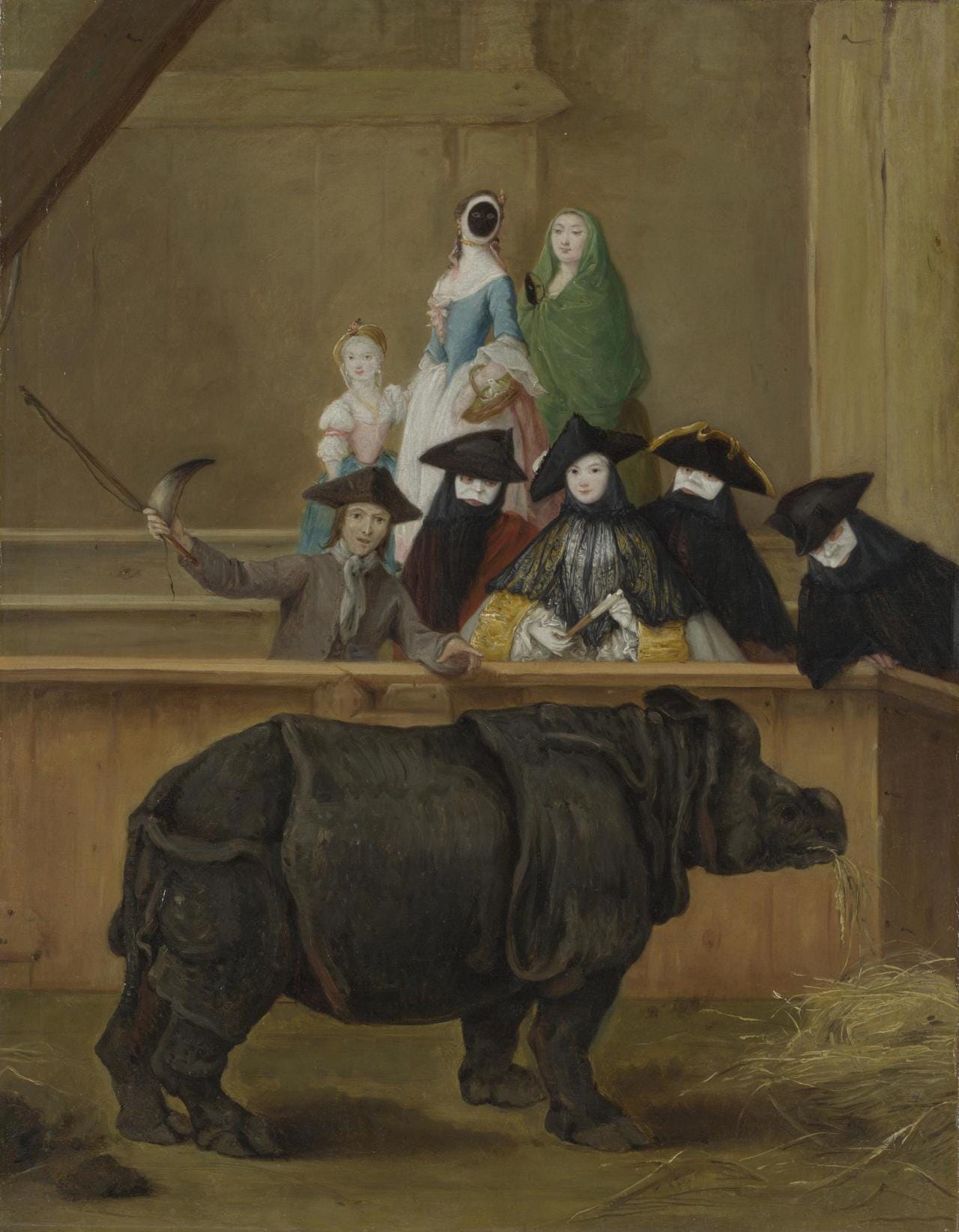 A dark rhinoceros eating hay in a wooden pen, watched by masked Venetians in a raised box A dark rhinoceros eating hay in a wooden pen, watched by masked Venetians in a raised box