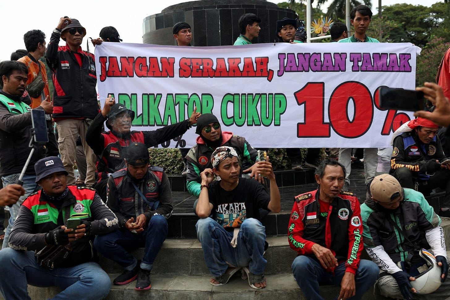 参与抗议的骑手举着写满了“不要太贪婪！10%的抽成对于平台足够了！”的横幅和标语。来源：路透社