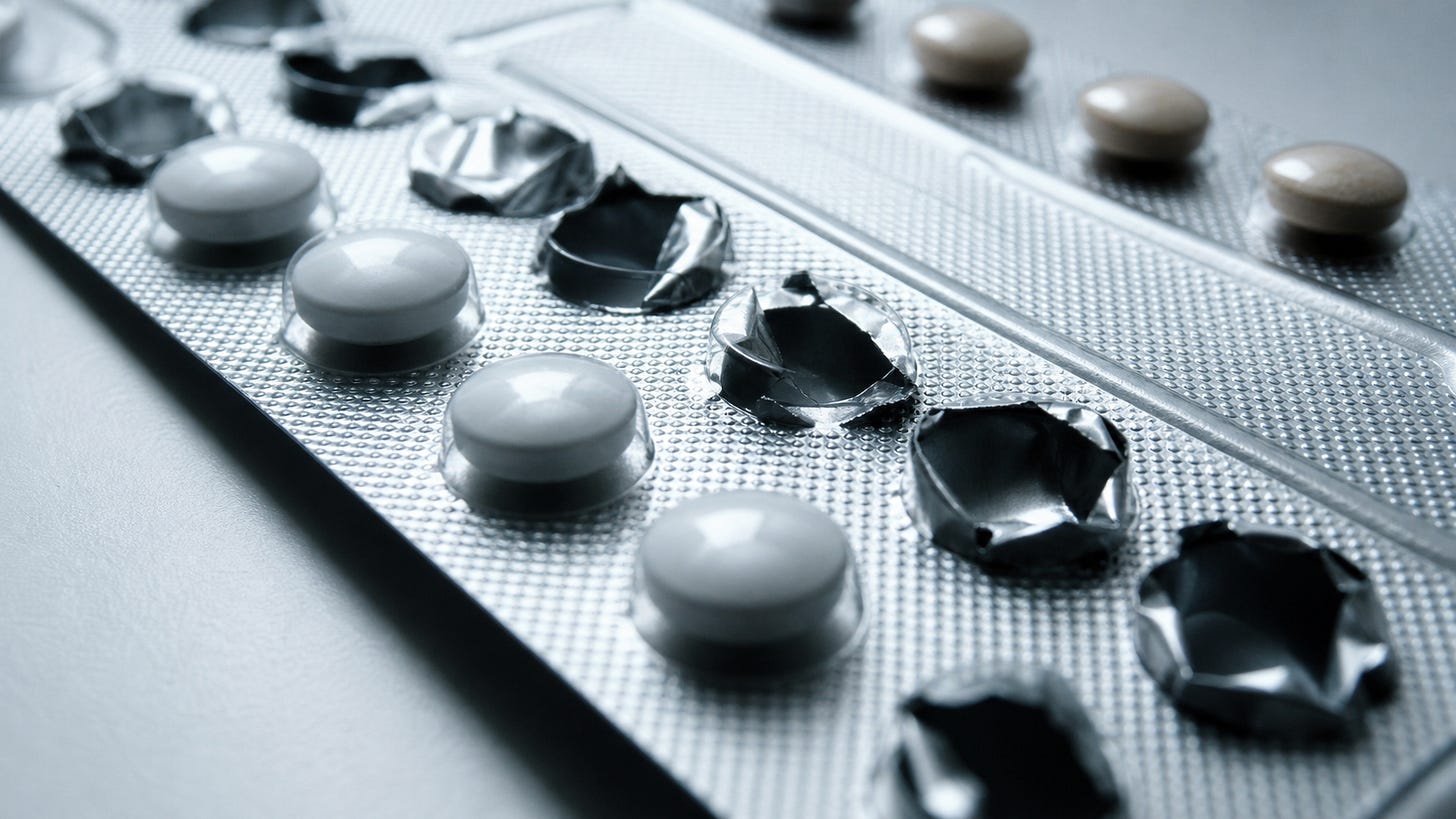 Macro 16:9 clinical close-up of generic birth control pill blister pack with cold blue-white lighting and deep shadows. Macro 16:9 clinical close-up of generic birth control pill blister pack with cold blue-white lighting and deep shadows.