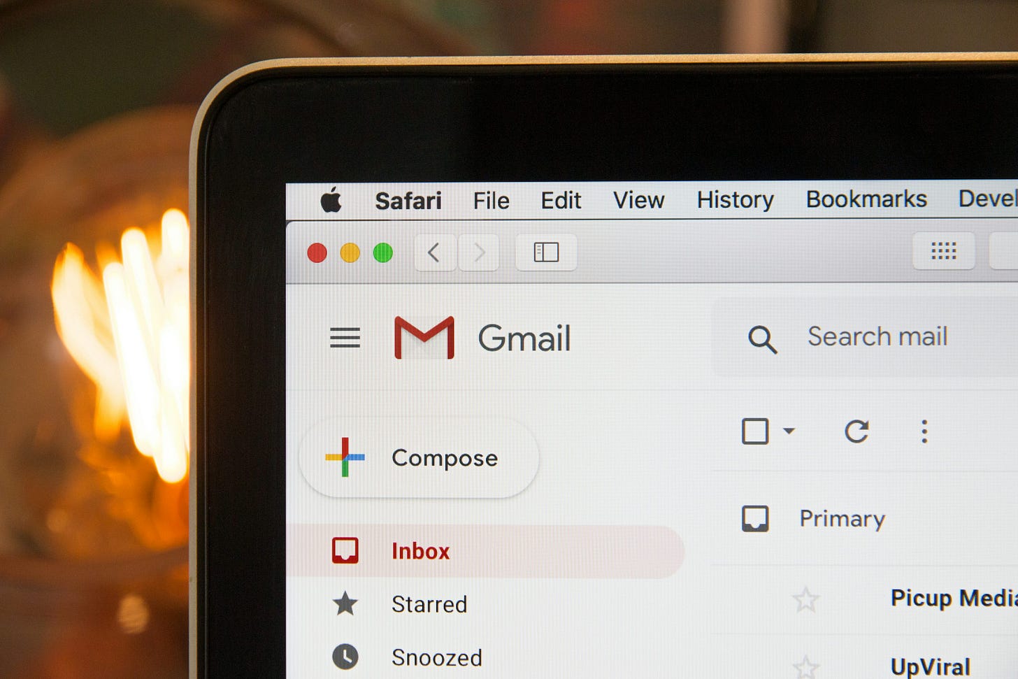 Close-up of a laptop screen showing the Gmail inbox and Compose button.