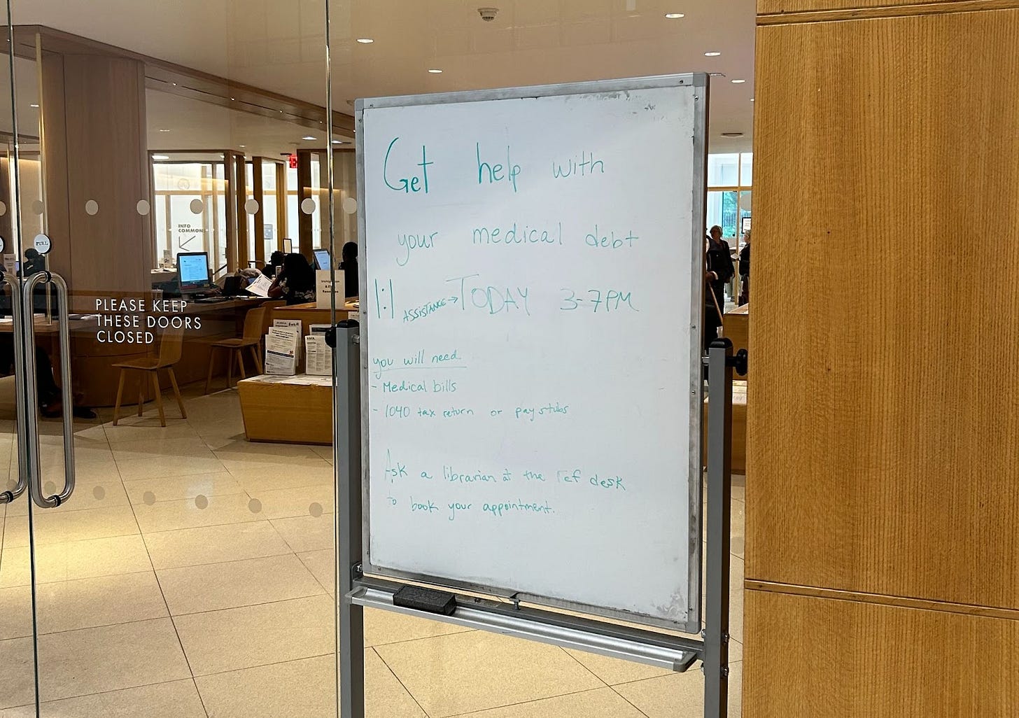Whiteboard with text on it in front of library doors Whiteboard with text on it in front of library doors