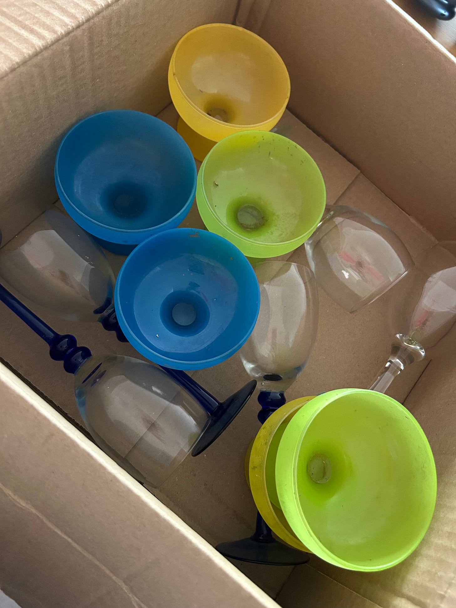 colorful dessert dishes, dirty in a box, with wine glasses