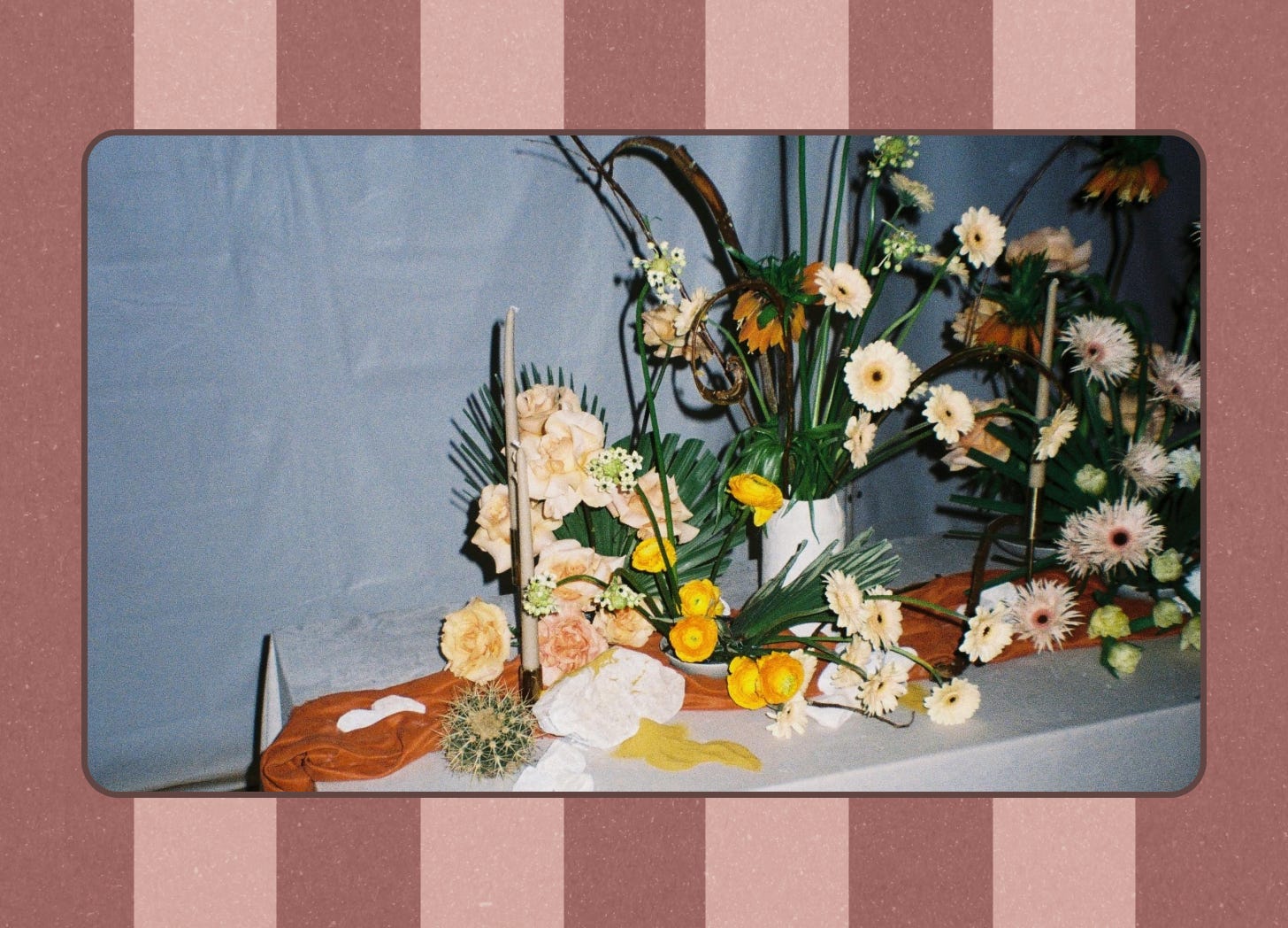 An image of a floral centerpiece on a table, set against a mauve striped background