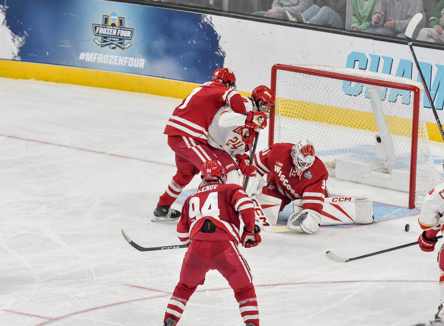 Goaltender Daniel Hauser puts goalie glove down to cover puck and stop scoring chance by Denvers Kieran Cebrian.