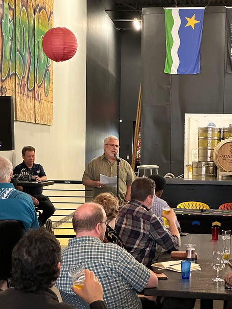 Five photos show various scenes at a party with people wearing flannels and tee shirts sitting down at tables, and people standing up at a microphone, and a panel of people sitting, one person speaking into a microphone. The last photo shows 7 people holding a yellow banner reading in black text: "Labor Education Service"