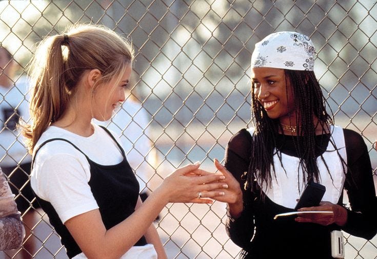This may contain: two young women standing next to each other near a fence