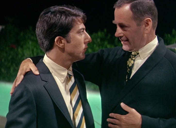 A person in a suit holding another person's shoulder

AI-generated content may be incorrect.