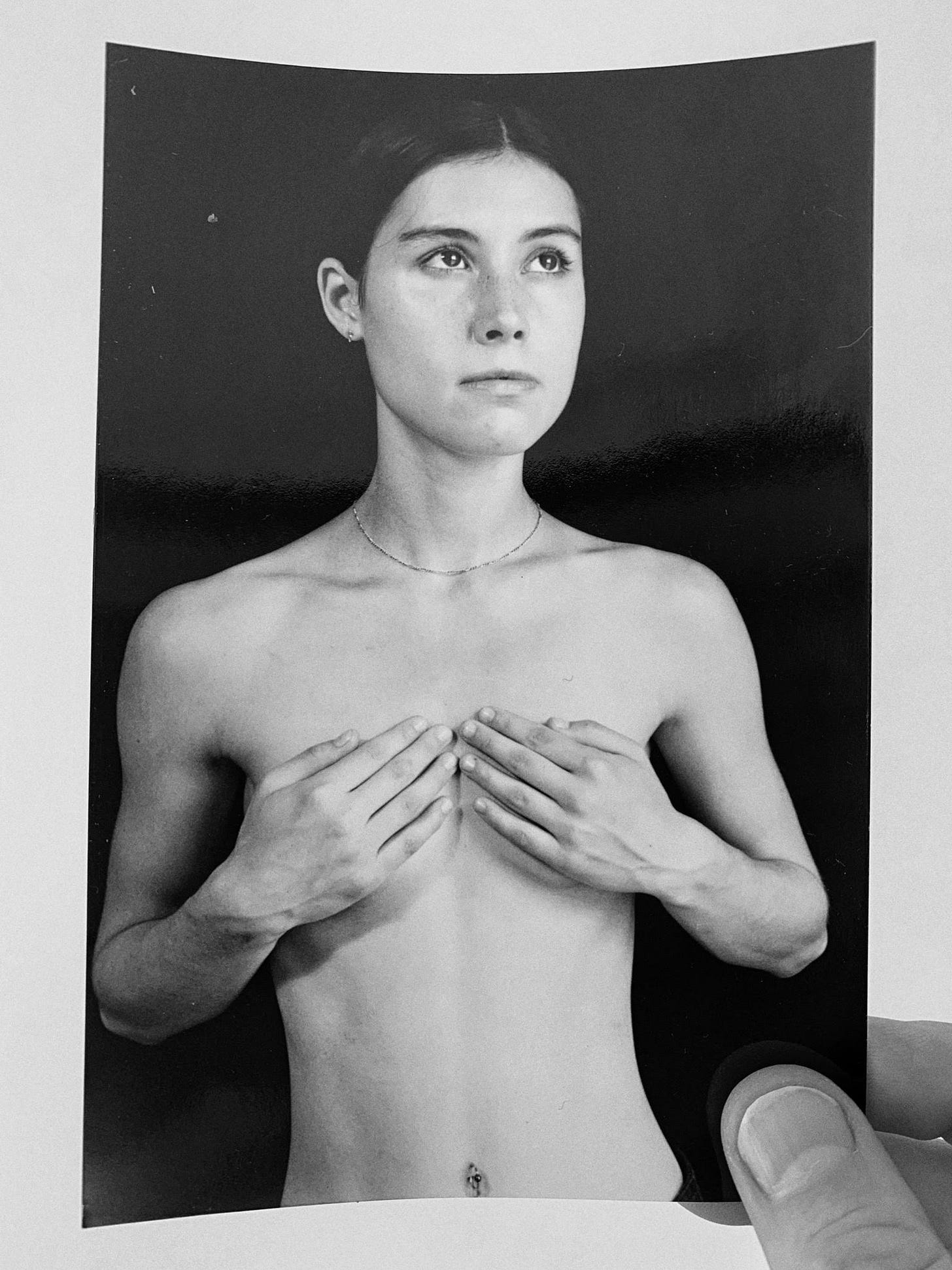 Black-and-white image of author, unclothed, in her 20s, holding hands over breasts, looking upwards