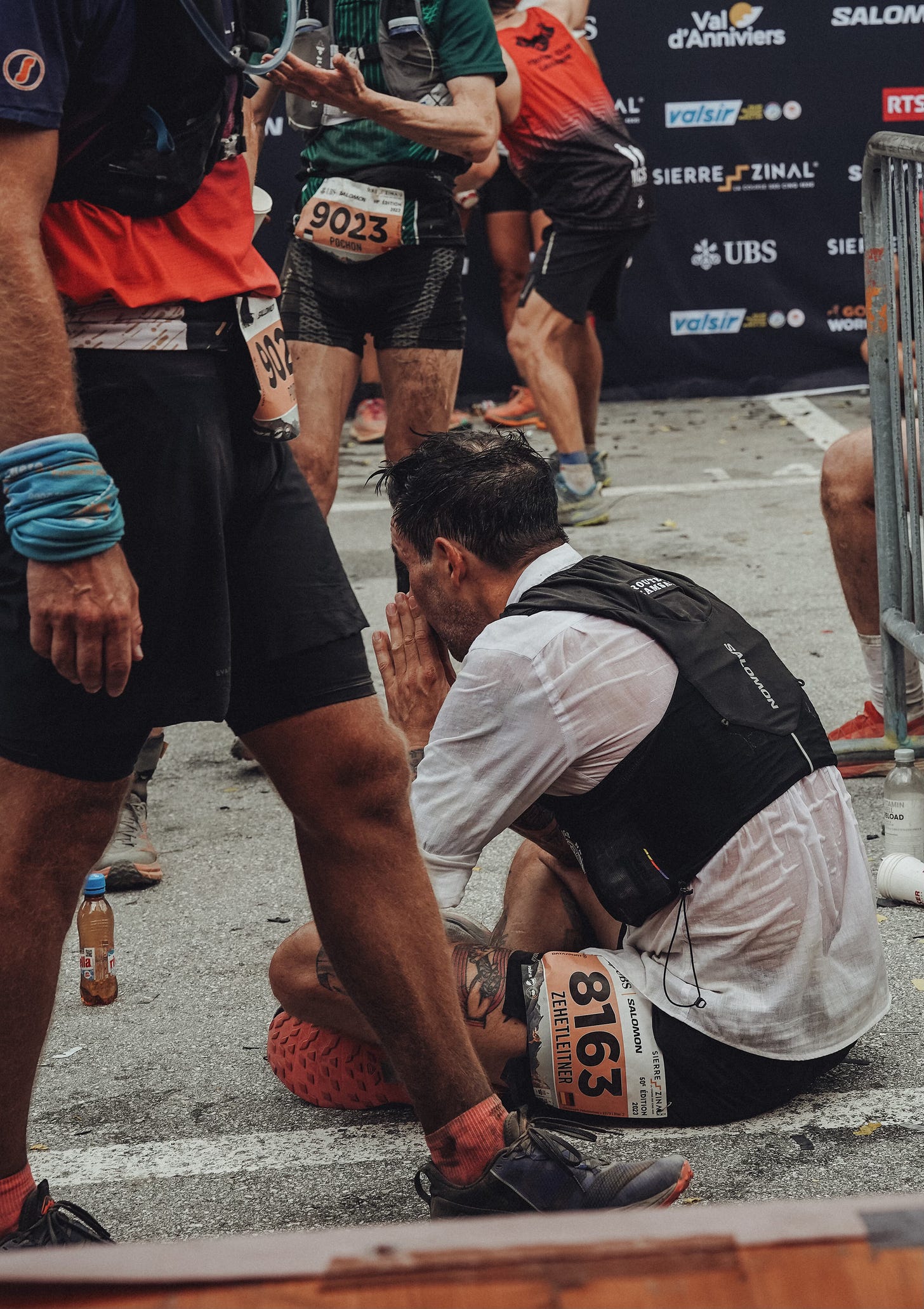 The author sitting on the ground of the finish line of Sierre-Zinal race 2023