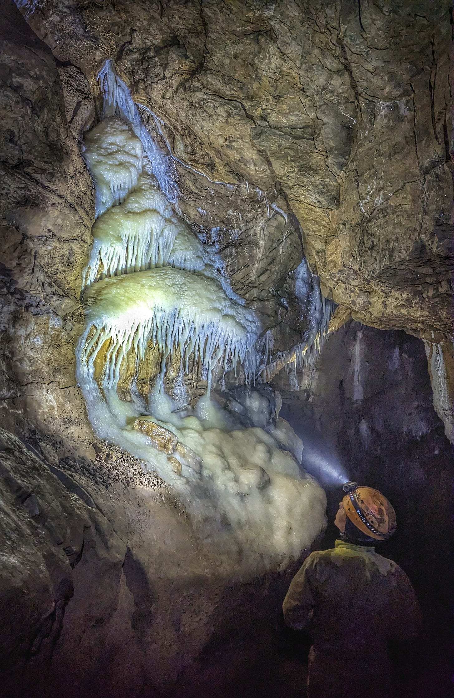 Picture of a caver examining rock formations in Peak Cavern, Castleton Picture of a caver examining rock formations in Peak Cavern, Castleton