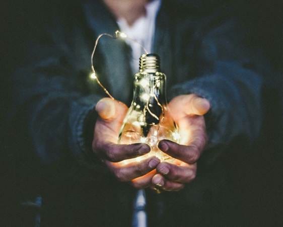 Photo of a man holding out a light bulb. I guess it's not too hot.