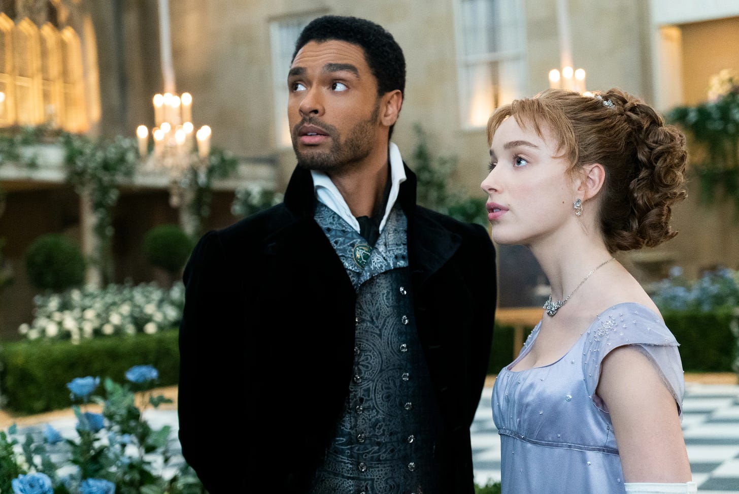 Simon and Daphne in Bridgerton, standing together and looking off-screen to the left