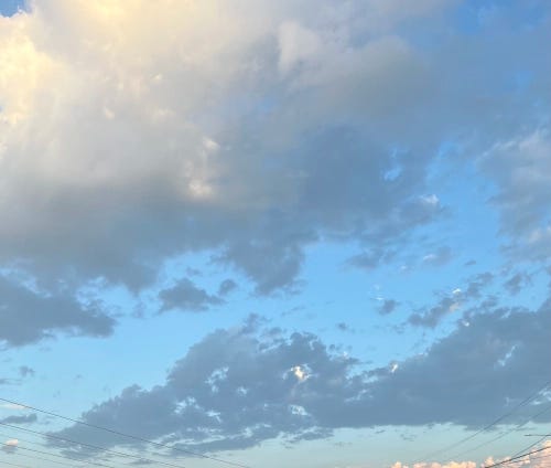 A vision of overhanging clouds chained together in a bright blue sky.