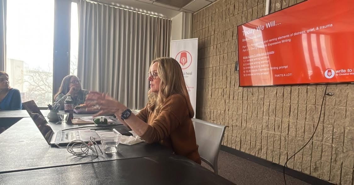 Blonde woman with glasses in front of a laptop gestures with hands while teaching a classroom full of students. A monitor behind her features an orange background and white type. Blonde woman with glasses in front of a laptop gestures with hands while teaching a classroom full of students. A monitor behind her features an orange background and white type.