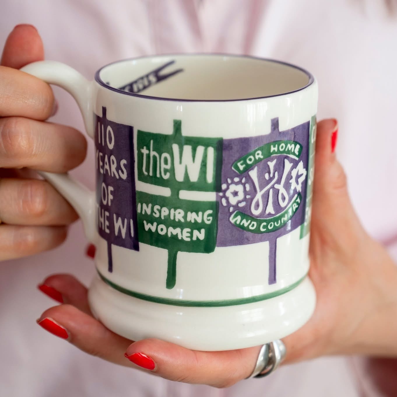 A mug depicting a badge and hand held banners for the WI empowering women