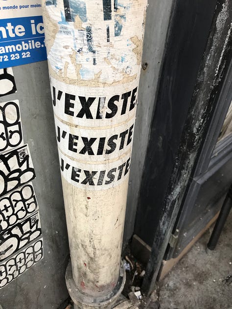 The J'existe sticker in three locations in Paris
