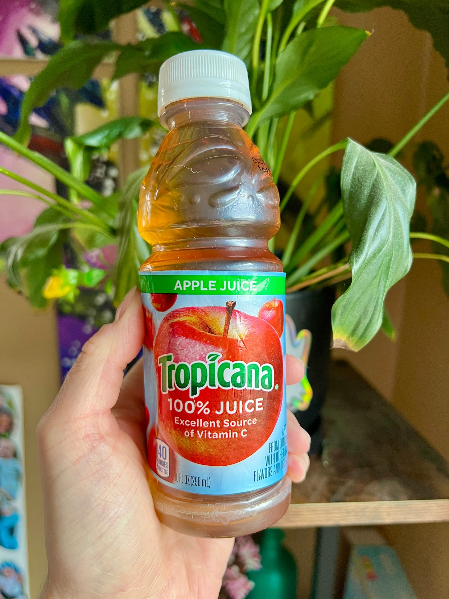 white hand holding tropicana apple juice bottle