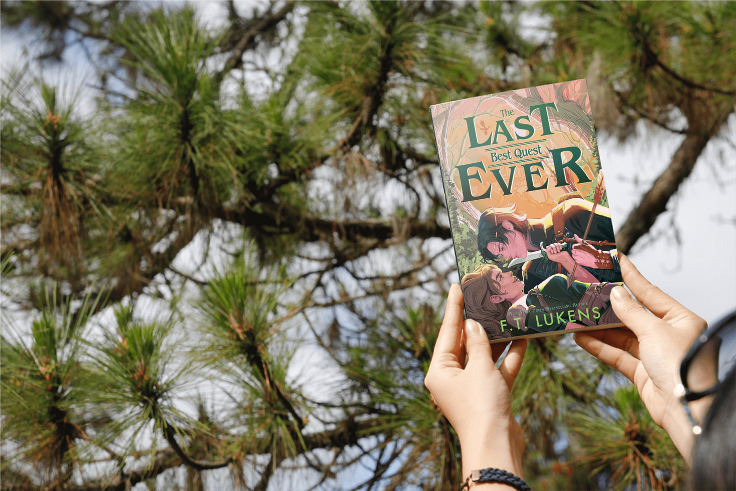 Book "Last Best Quest Ever" by F T Lukens held in front of a evergreen tree. Book "Last Best Quest Ever" by F T Lukens held in front of a evergreen tree.