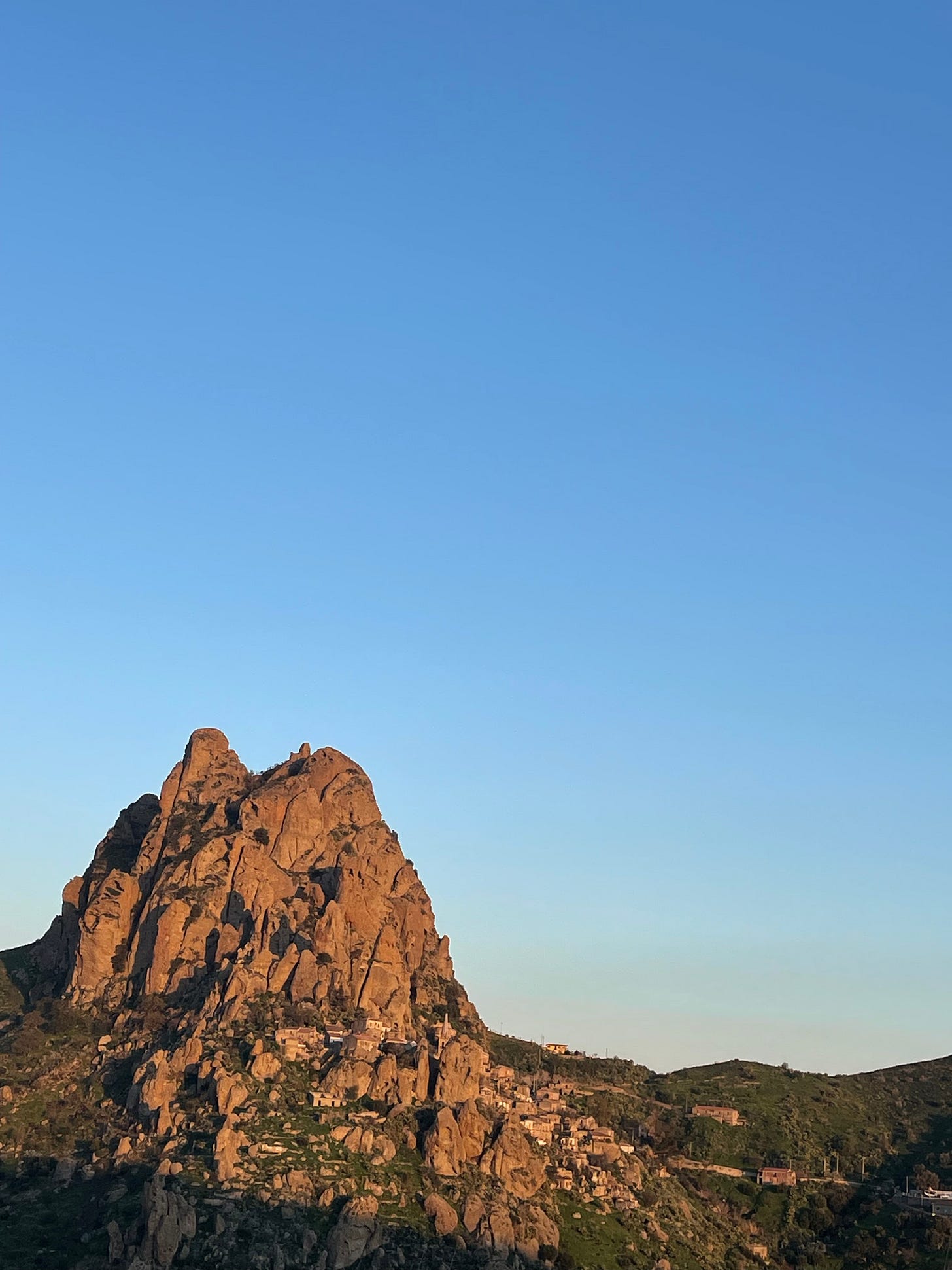 A huge monolith - the rock of Pentedattilo - with the town of Pentedatillo below.