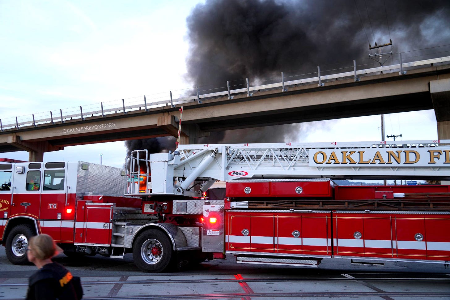 A fire department ladder truck arrives at a fire at a transfer station in East Oakland on Apr. 28, 2026. Two RVs caught fire in the enclosed lot. (Photo: Shutterstock / Oakland Report) A fire department ladder truck arrives at a fire at a transfer station in East Oakland on Apr. 28, 2026. Two RVs caught fire in the enclosed lot. (Photo: Shutterstock / Oakland Report)