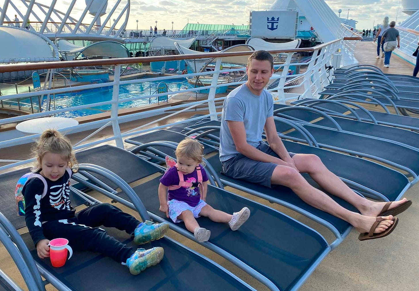 a baby and a toddler sit on the open deck of a cruise ship
