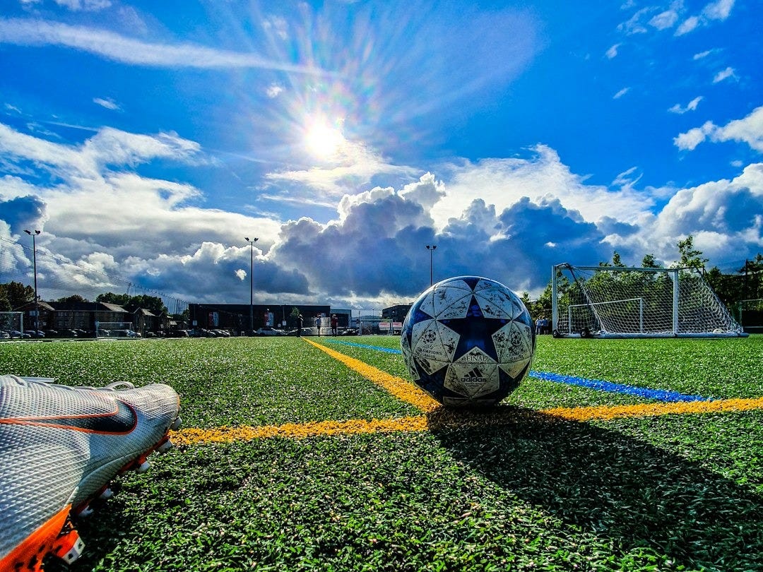 blue and grey soccer ball on green field under white and blue sky during daytime