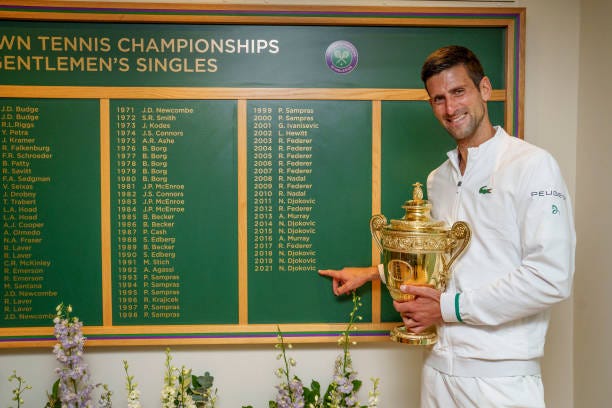 Novak Djokovic of Serbia celebrates with the trophy in front of the honours board and points to his name after winning his men's Singles Final match...