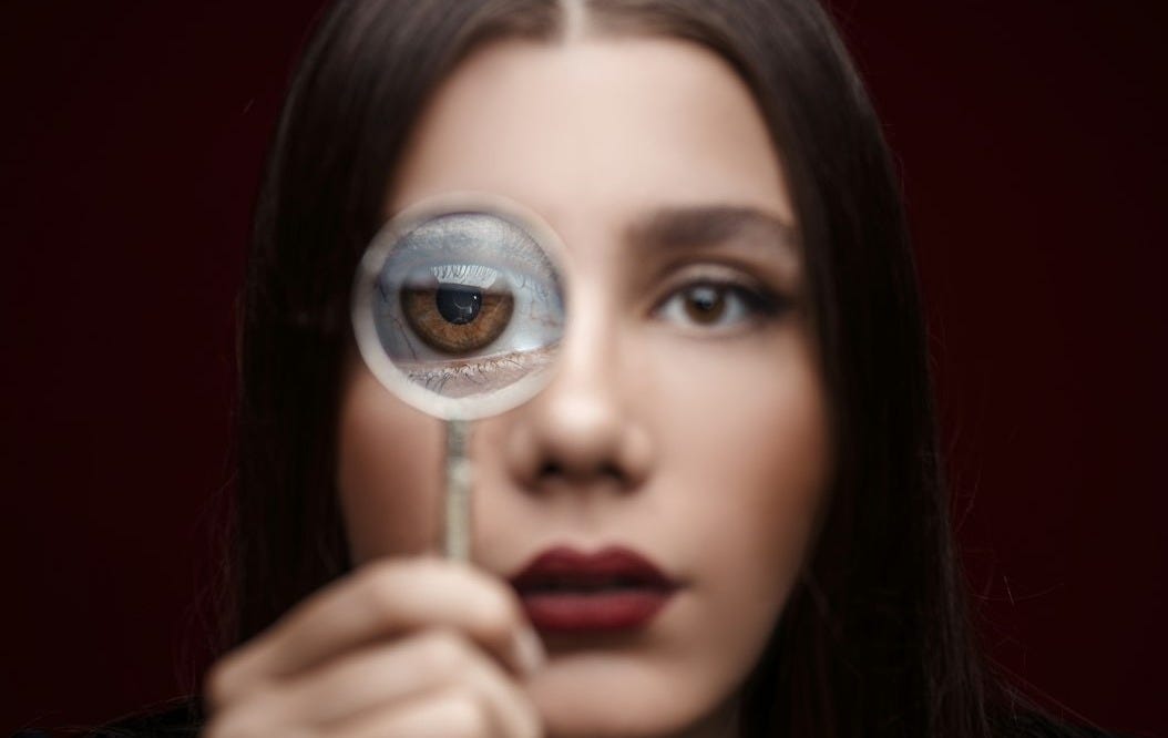 woman looking through magnifying glass woman looking through magnifying glass