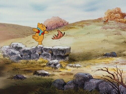 This may contain: winnie the pooh flying over rocks and trees