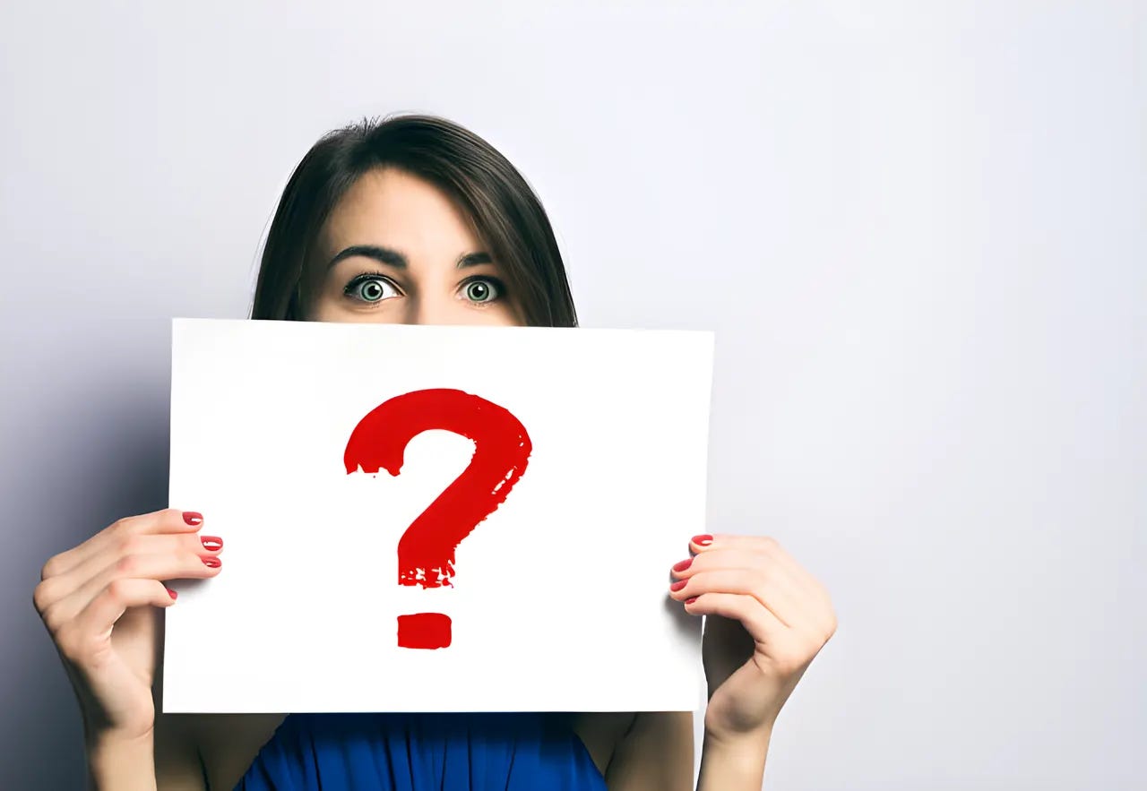 Woman holding a sign in front of her face with a red question mark on it.
