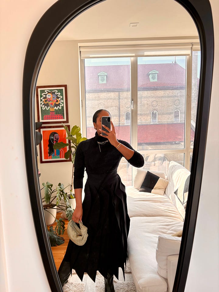 Two full-body mirror selfie photos side by side with a Black woman posing in an all black outfit including a turtleneck and dramatic skirt.