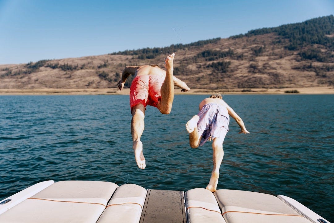 two people jumping off a boat into the water