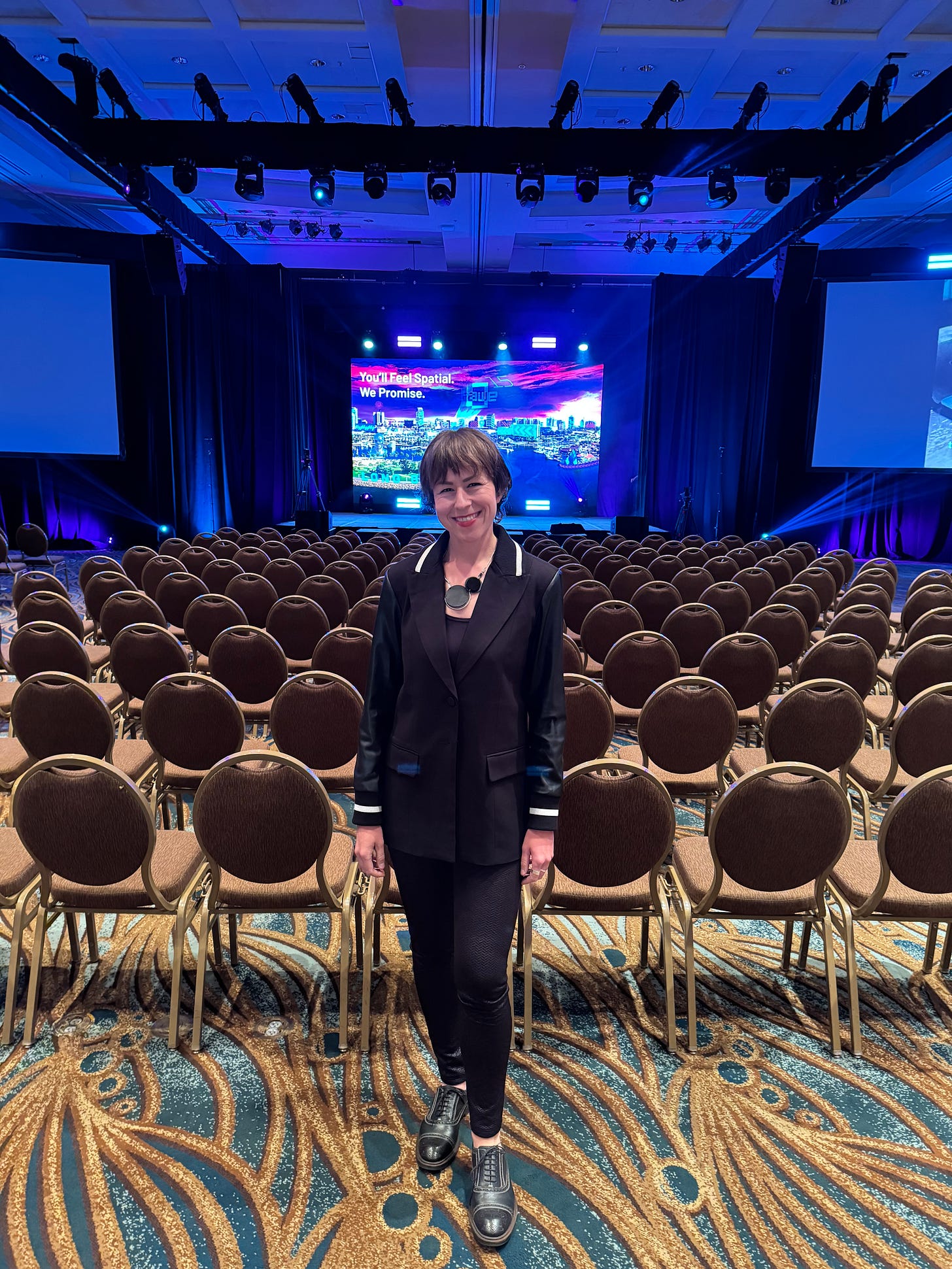 Stef Hutka standing in front of rows of empty main stage chairs, after Day 1 keynotes wrapped up.
